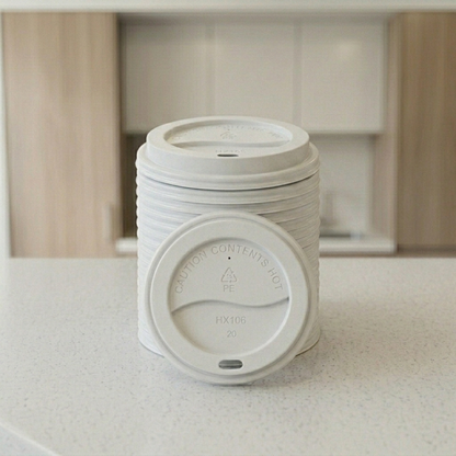 Stack of white hot coffee cup lids, model HX106, on a breakroom counter