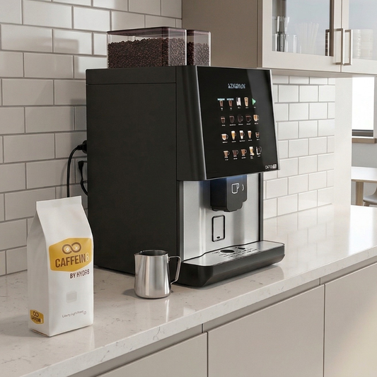 CAFFEIN8 by HYDR8 Liberty Light Roast coffee beans next to Caffein8 office coffee machine in modern workplace break room