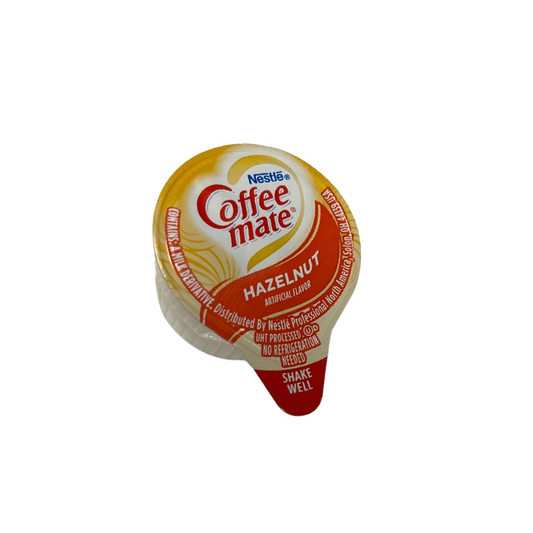 Nestlé Coffee mate Hazelnut liquid creamer single-serve cup on a white background, top view showing the gold and orange lid and Shake Well tab